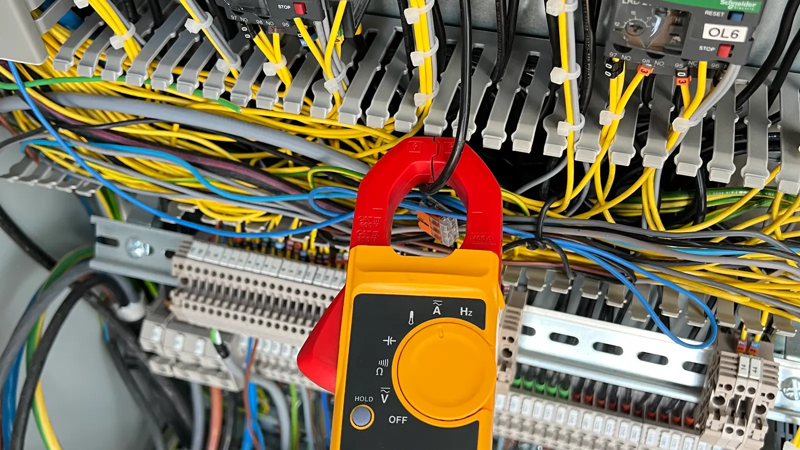 Contrôle à la pince ampèremétrique dans une armoire électrique d'atelier